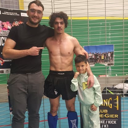 Combattant torse nu avec son coach et un jeune du club